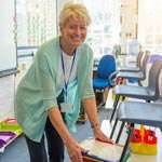 Smiling teacher leaning over student desks