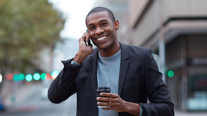 Man smiling on the phone walking on the street