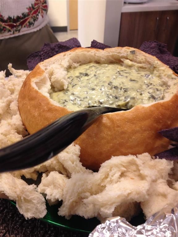 A warn bread bowl filled with artichoke dip